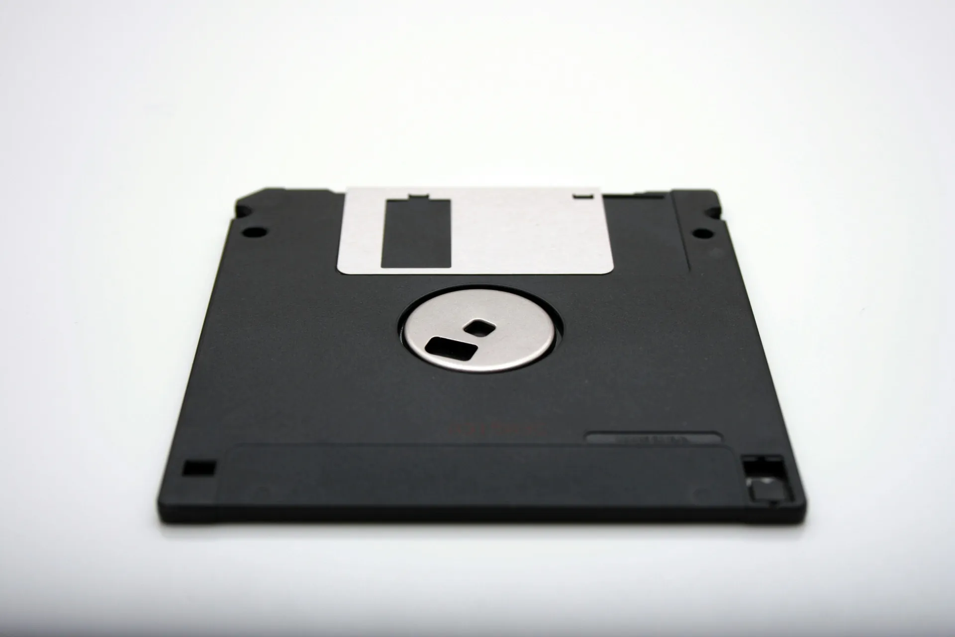 Vista cercana de un disquete negro sobre un fondo blanco, un símbolo icónico del almacenamiento informático de los años 80 y 90.
